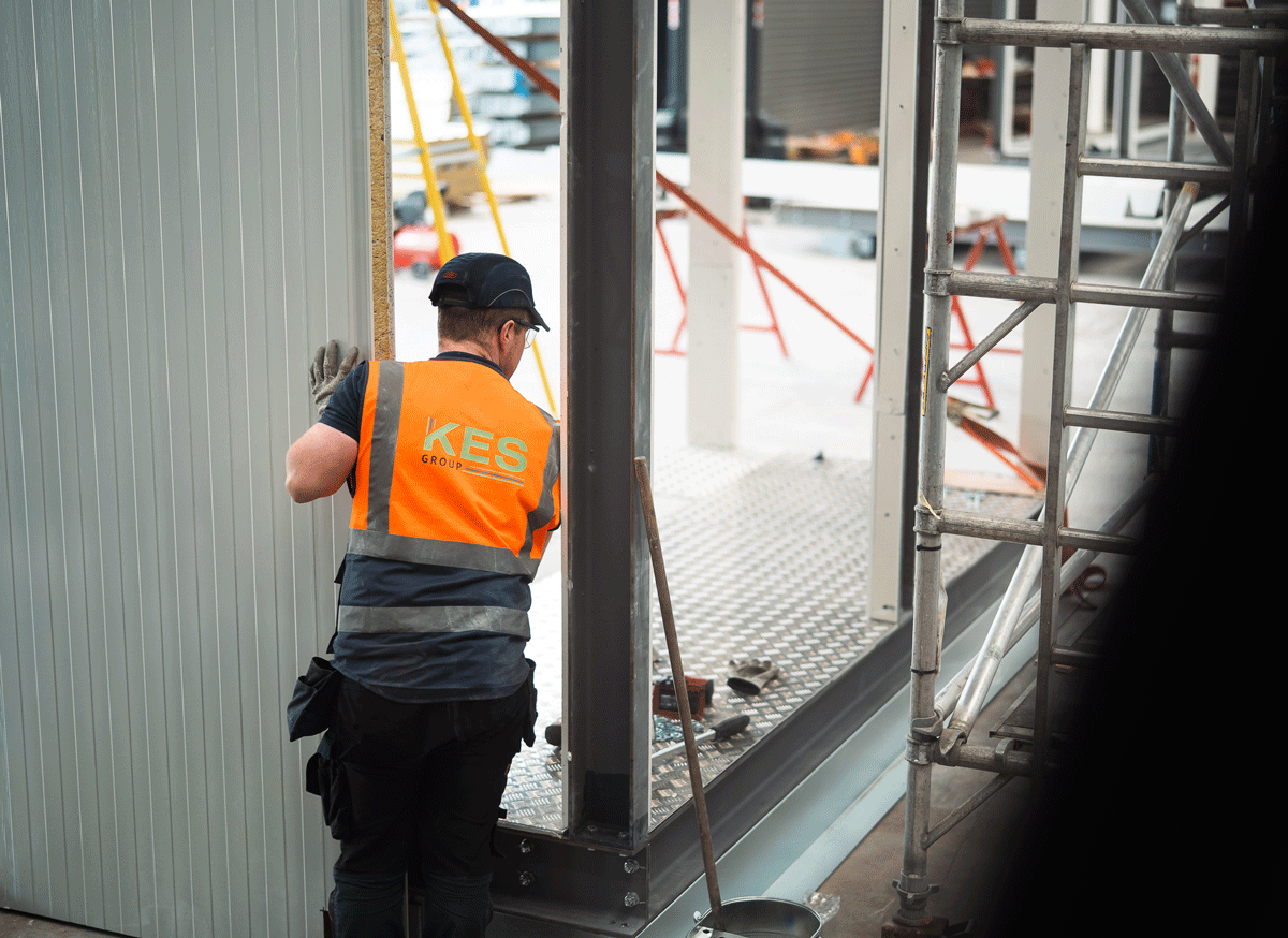 Workman with high vis standing next to steel beam on modular building 